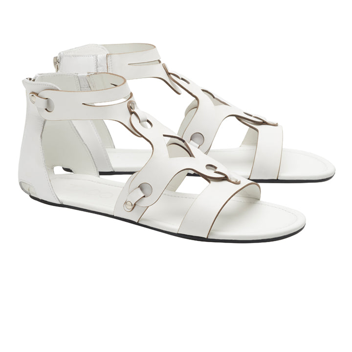 Wir präsentieren die MAROQ White von ZAQQ, ein schickes Paar Sandalen im Gladiator-Stil, fachmännisch aus Nappaleder gefertigt. Diese eleganten Sandalen haben offene Zehen, Knöchelriemen, dekorative Metallringe und einen praktischen Reißverschluss auf der Rückseite. Komplettiert mit langlebigen, flachen Kautschuksohlen vereinen sie auf elegante Weise Stil und Stärke.