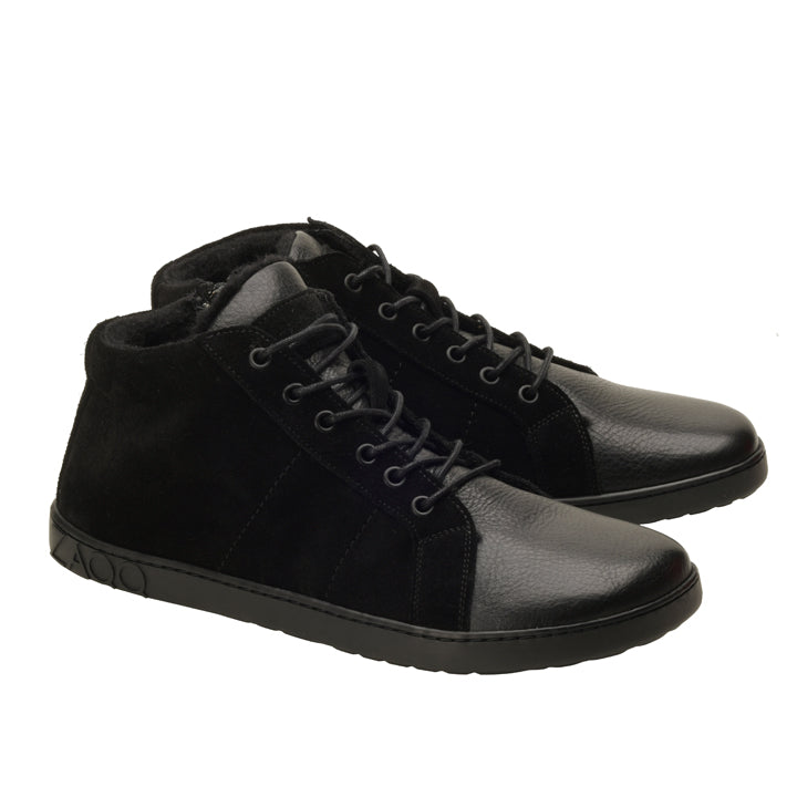 Wir präsentieren den ZAQQ QORE Mid Winter Black, ein Paar High-Top-Sneaker in auffälligem Schwarz, die Leder- und Wildledertexturen für einen Hauch von Raffinesse kombinieren. Sie kommen mit schwarzen Schnürsenkeln und einer dunklen Gummisohle, die kunstvoll in einem Winkel positioniert ist, um sowohl die Seiten- als auch die Vorderansicht zu zeigen.