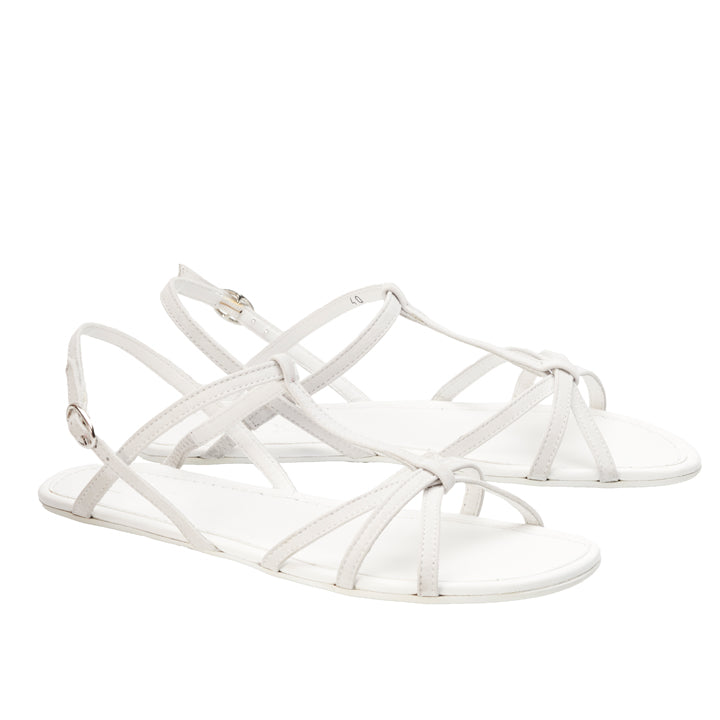 Entdecken Sie die weißen QADA-Sandalen von ZAQQ, die mit minimalistischer Eleganz entworfen wurden. Diese Barfußsandale aus hochwertigem Nappaleder zeichnet sich durch dünne Riemen aus, die sich über den oberen Teil und den Knöchel kreuzen und mit einer seitlichen Schnalle versehen sind. Die flachen Sohlen spiegeln Einfachheit und Stil wider.