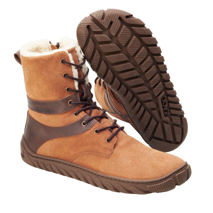 Wir präsentieren den VIVAQ Brown von ZAQQ: Diese Outdoor-Stiefel zeichnen sich durch eine stilvolle Kombination aus braunem Wildleder und Leder mit Schnürdetails aus. Sie verfügen über eine dicke, strukturierte Gummisohle, die für Strapazierfähigkeit bei jedem Abenteuer ausgelegt ist. Das weiche und warme Innenfutter ist sichtbar und erhöht den Komfort für Ihre Füße. Ein Stiefel steht aufrecht, während der andere geneigt ist, um die Bereitschaft der robusten Sohle für raue Erkundungen zu demonstrieren.