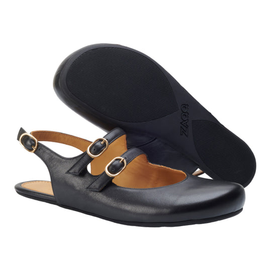 Ein Paar flache Slingback-Schuhe QOMET aus schwarzem Leder von ZAQQ hat doppelte Schnallenriemen und ein hellbraunes Innenfutter. Ein Schuh steht aufrecht, während der andere auf der Seite liegt, wodurch die rutschfeste schwarze Sohle und das Markenlogo hervorgehoben werden – eine perfekte Kombination aus Stil und Komfort.