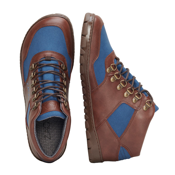 Die HIQE Mid Vegan Blue Waterproof Wanderschuhe von ZAQQ sind robust und wasserdicht und bestehen aus braunem Leder mit blauen Stoffeinsätzen. Sie haben robuste Schnürsenkel und Metallösen, ergänzt durch eine langlebige Gummisohle, die von oben und von der Seite gut zu sehen ist.