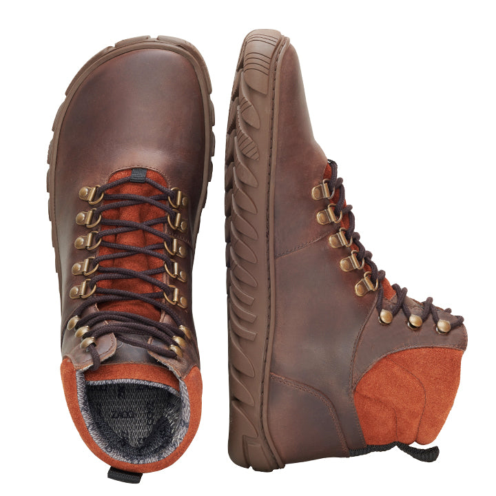 Ein Paar robuste WALQ Brown Waterproof Wanderstiefel von ZAQQ mit orangefarbenen Akzenten, gefertigt aus Veloursleder. Ein Stiefel ist aufrecht ausgestellt, um die Seitenansicht zu zeigen, während der andere liegend positioniert ist, um die Schnürsenkel und die strukturierte Sohle hervorzuheben. Diese robusten Winterschuhstiefel sind mit Metallösen für zusätzliche Haltbarkeit ausgestattet.