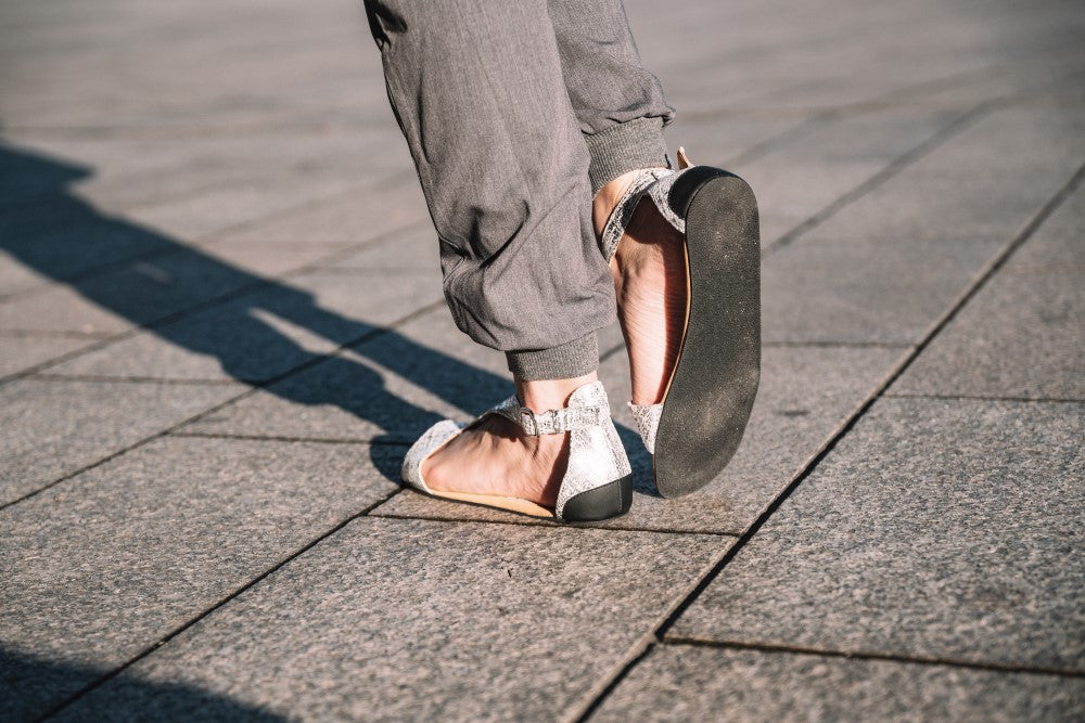 CLIQ Silver-Sandalen von ZAQQ mit silbernem Metallic-Finish, offenen Zehen, Knöchelriemen und einer Kautschuksohle auf weißem Hintergrund.