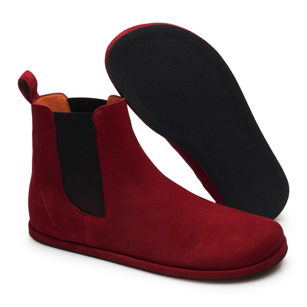 Die EQUITY Berry Chelsea Boots von ZAQQ bestechen durch ihr auffälliges rotes Wildlederfinish, ergänzt durch elegante schwarze elastische Seiten. Ein Stiefel steht aufrecht und zeigt das lebendige Design, während der andere seine strukturierte schwarze Sohle offenbart.