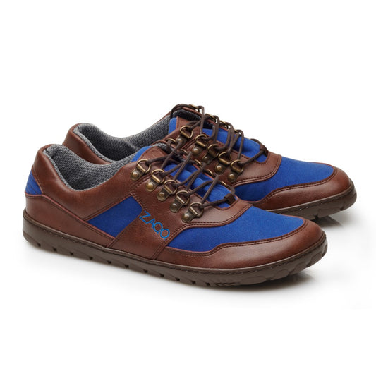 Wir präsentieren die wasserdichten Schuhe HIQE Low Brown Blue von ZAQQ, die aus einer Mischung aus veganem Material mit braunem Leder und blauen Stoffeinsätzen gefertigt sind. Diese stilvollen Merkmale werden durch braune Schnürsenkel, die durch Metallösen gefädelt sind, und eine robuste braune Sohle ergänzt, die sich elegant vor einem schlichten weißen Hintergrund präsentiert.