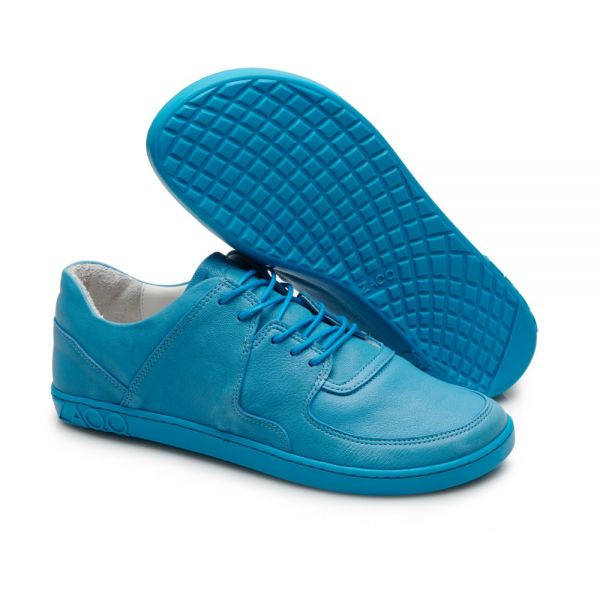 Ein Paar leuchtend blaue Sneaker von ZAQQ, von denen einer flach liegt und der andere hochgestellt ist, um die strukturierte Sohle zu präsentieren. Diese IVIQ Blue-Schuhe haben Schnürsenkel und ein elegantes Design und vereinen gekonnt Stil und Komfort für moderne Abenteurer.