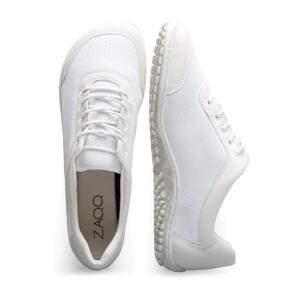 Die SQIP White Sneaker von ZAQQ zeichnen sich durch ein minimalistisches Design mit strukturierter Sohle und Schnürsenkeln aus, ergänzt durch atmungsaktives Mesh. Der Markenname ZAQQ ist elegant auf der Innensohle dieser veganen Barfußschuhe angebracht, die sowohl von oben als auch von der Seite bewundert werden kann.