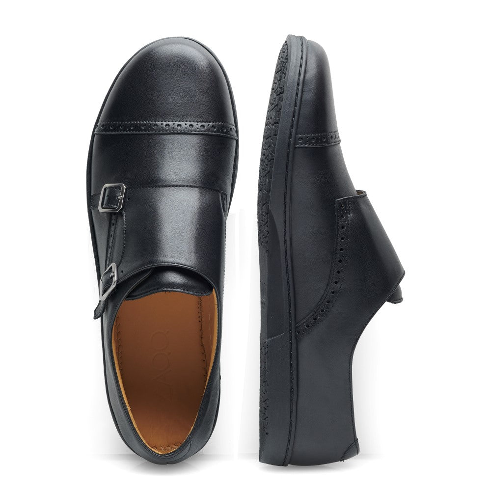 Der MONQ Captoe Black von ZAQQ ist der Inbegriff von Eleganz. Ein Schuh ist von oben zu sehen, wo er seine Schnalle und das Captoe-Design hervorhebt, und der andere von der Seite, wo er seine glatte Silhouette und die detaillierten Nähte zur Schau stellt. Diese eleganten schwarzen Lederschuhe sind perfekt für jeden Businessschuh-Anlass.