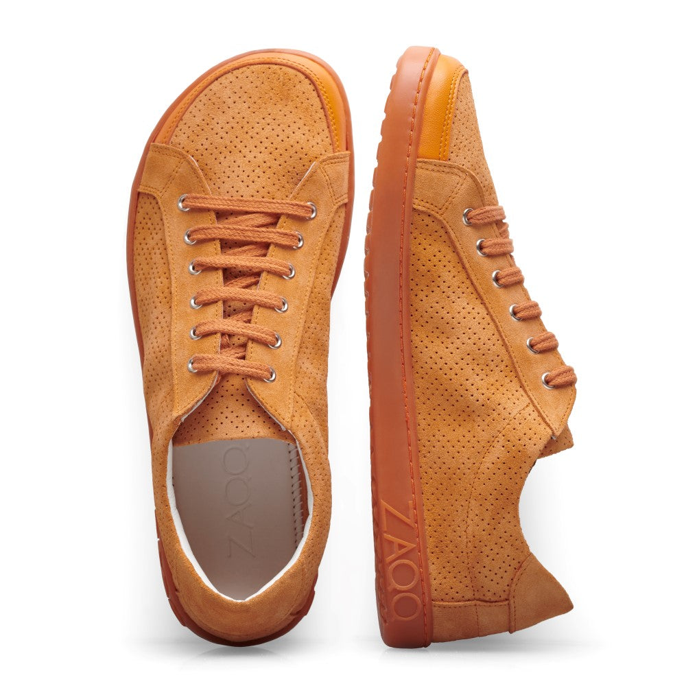 Der SLOQ Orange von ZAQQ besteht aus zwei Barfuß-Sneakern aus Veloursleder in Orange mit perforiertem Design. Ein Sneaker ist von oben mit sichtbaren Schnürsenkeln zu sehen, während der andere seitlich ausgerichtet ist und eine strukturierte Kautschuksohle und Ferse zeigt.