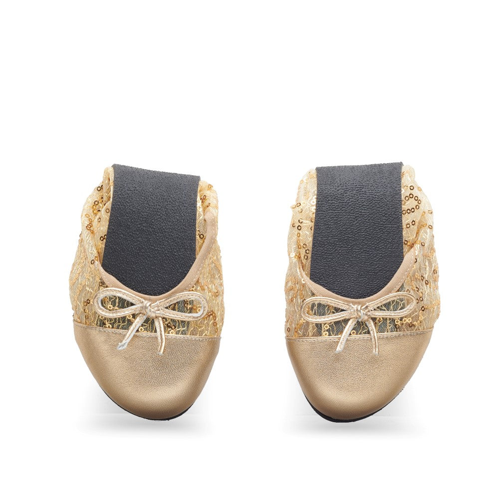 Nebeneinander ausgestellt sind die TWIST GUATEQUE Gold Ballerinas von ZAQQ mit paillettenbesetztem Mesh-Oberteil und glänzenden metallischen Zehenkappen. Jeder Schuh hat oben eine kleine Schleife, eine flexible Sohle und schwarze Gummibänder in der Mitte für einen sicheren Sitz und zusätzlichen Komfort.